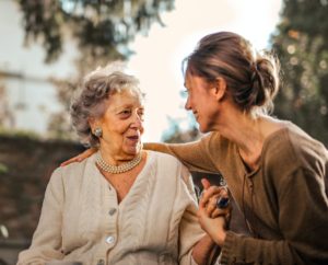 Young woman holding hands with, and with her arm around a loved one, a senior woman.