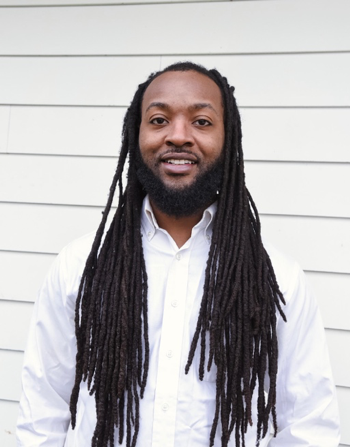 Photo of Patrick Holmes, a young black man with long braided hair who is smiling